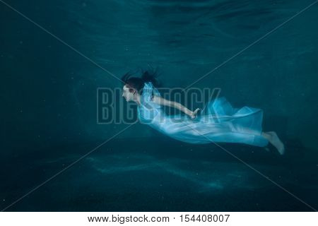 Woman at the bottom of the pool she under the water like a fairy tale.