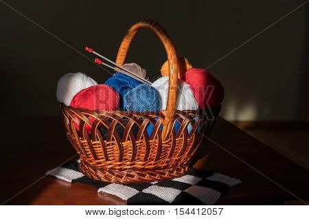 multicolored tangles lie to a basket with knitting needles and products
