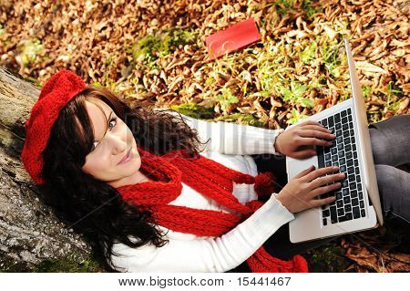 Ritratto di close-up di una bella studentessa d'autunno lavorando con il computer portatile