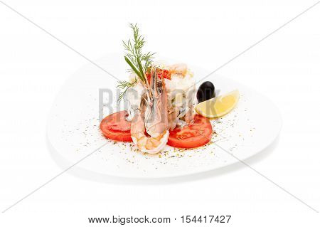 Seafood dish with shrimps. Isolated Delicious Salad with shrimps, tomatoes & fennel garnished with a olives & lemon on a white plate.