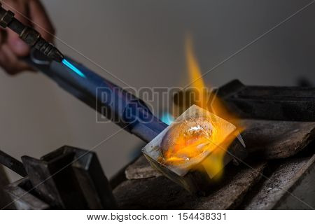 Melting Silver Grains to liquid state in crucible with blowtorch; Goldsmith Workshop; Close-up