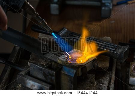 Melting a Silver Ingot to liquid state in crucible with blowtorch; Goldsmith Workshop; Close-up