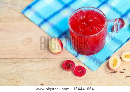 Carandas-plum  juice  in a glass on wooden background