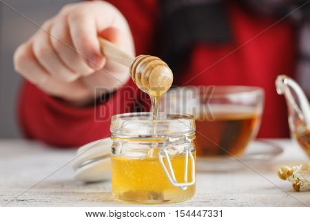 Man Hold Cup Of Hot Tea In Glass Cup, Jar Of Honey, Honey Dipper On The Old Wooden Background