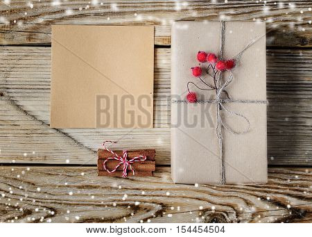 Christmas packege and letter with bunch of cinnamon on wood.