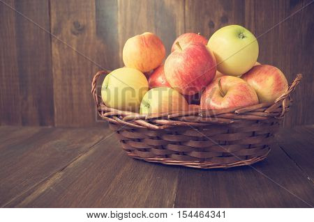 Apples in basket on wooden rustic background. Autumn and harvest concept selective focus toned horizontal