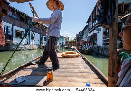 ZHUJIAJIAO CHINA - AUGUST 30 2016: Boatman transports tourists by Chinese gondola on canal of ancient water town with a history of more than 1700 years in Zhujiajiao China on August 30 2016.