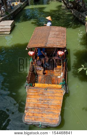 ZHUJIAJIAO CHINA - AUGUST 30 2016: Boatman transports tourists by Chinese gondola on canal of ancient water town with a history of more than 1700 years in Zhujiajiao China on August 30 2016.