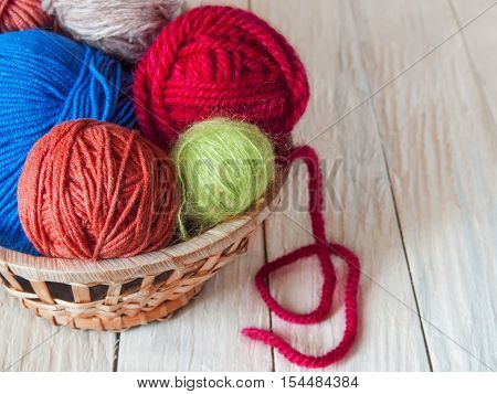 Yarn for hand knitting in different colors needles hooks lie on a wooden table