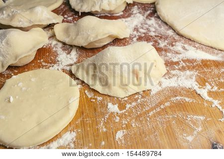 Preparing homemade ukrainian dumplings or varenyky cutting the round pieces of dough with cherry national ukrainian food