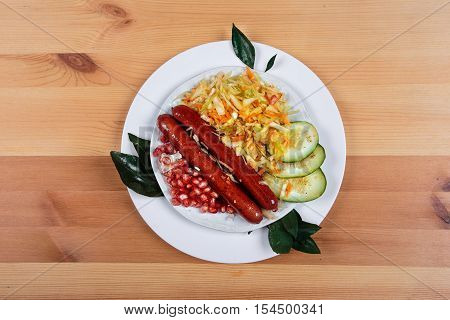 Delicious sausages with vegetables on a wooden light background