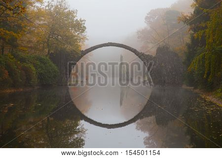 Rakotzbruecke (Devil's bridge) in early morning mist, in autumn, Kromlau, Germany