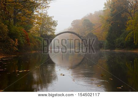Rakotzbruecke (Devil's bridge) in early morning mist, in autumn, Kromlau, Germany