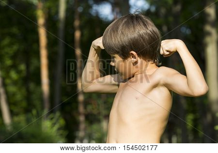Portrait of a boy in nature which shows his muscles