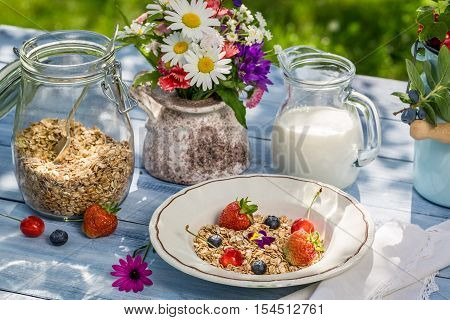 Breakfast with oatmeal fruit and milk on old wooden table