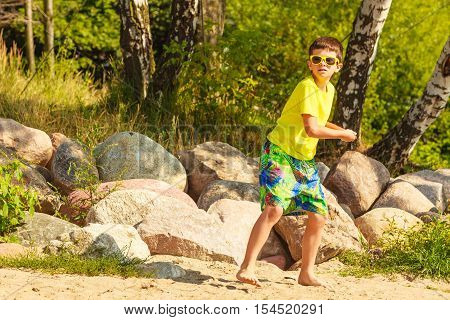 Play and fun concept. Little playful enjoyable boy kid throwing frisbee disc. Male child having fun playing outdoor on beach.