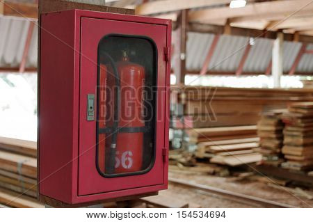 Fire extinguishers on blurry stack of wood in warehouse