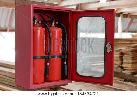 Fire extinguishers on blurry stack of wood in warehouse