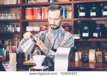 Portrait of professional bartender preparing alternative coffee in coffee machine