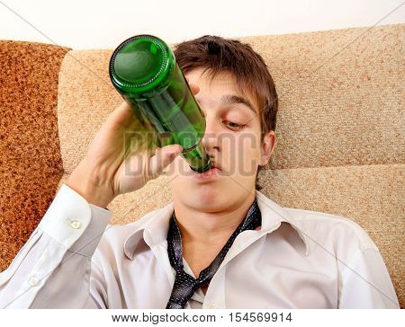 Teenager drinks a Beer on the Sofa at the Home