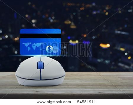 Wireless computer mouse with blue credit card on wooden table over blur light city tower Online e-payment concept