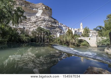 Alcala del Jucar Spain - October 29 2016: Roman bridge located in the central part of the town to its passage by the river Jucar Church of San Andres styles late Gothic and Neoclassic take in Alcala of the Jucar Albacete province Spain