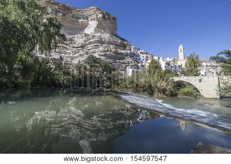 Alcala del Jucar Spain - October 29 2016: Roman bridge located in the central part of the town to its passage by the river Jucar Church of San Andres styles late Gothic and Neoclassic take in Alcala of the Jucar Albacete province Spain