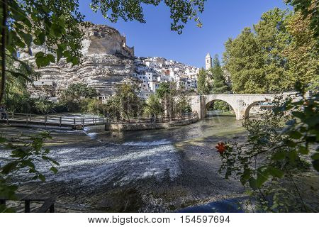 Alcala del Jucar Spain - October 29 2016: Roman bridge located in the central part of the town to its passage by the river Jucar at the top of mountain limestone is situated castle of Almohad origin of the century XII take in Alcala of the Jucar Albacete