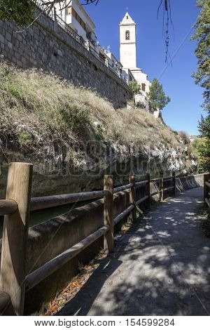 Alcala del Jucar Spain - October 29 2016: Passage along the river Jucar left the church of San Andres styles late Gothic and Neoclassic take in Alcala of the Jucar Albacete province Spain
