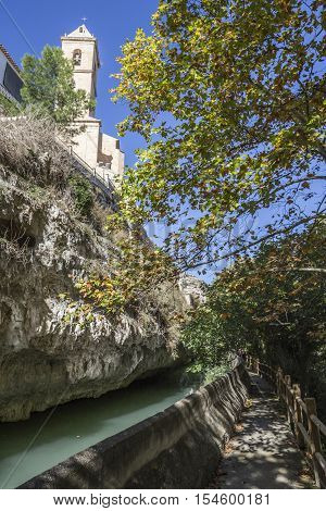 Alcala del Jucar Spain - October 29 2016: Passage along the river Jucar left the church of San Andres styles late Gothic and Neoclassic take in Alcala of the Jucar Albacete province Spain