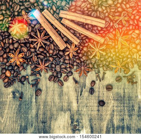 Coffee beans with spices cinnamon cloves and star anise. Vintage style wooden background with light leaks