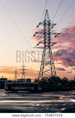 Tower of power lines in the suburbs in the evening after the rain against the backdrop of pink clouds