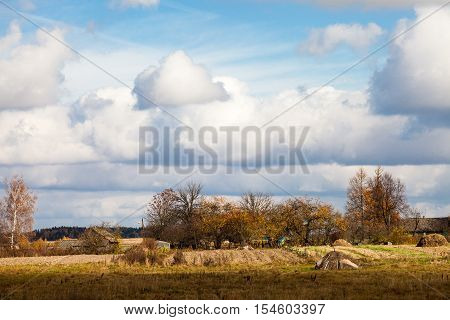 Country landscape scenic with village in background on sunny cloudy day in autumn in Belarus