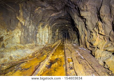 Old abandoned iron shaft mine tunnel with sulfur dirt