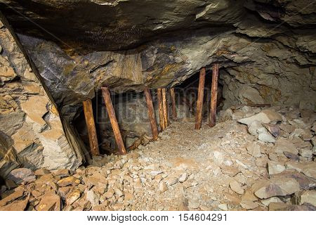 Old abandoned gold mine shaft tunnel passage with cavity and wooden stands barring