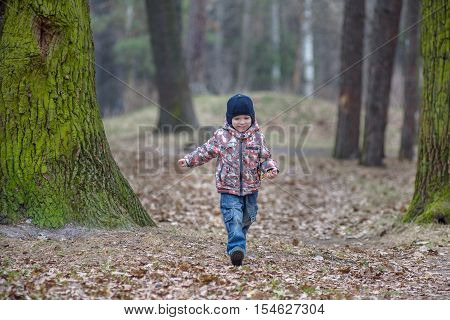 kid running in the outumn forest. Boy happy running in fallen leaves to his mother.