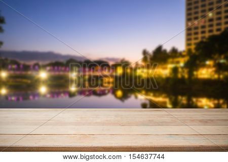 Empty of wood desk form and bokeh light of night city scape background for product presentation display montage.