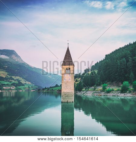 Beautiful view of the lake Resia. Famous tower in the water. Alps, Italy, Europe. Toned like Instagram filter