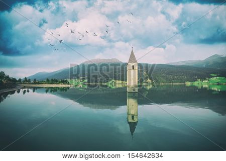Beautiful view of the lake Resia. Famous tower in the water. Alps, Italy, Europe. Toned like Instagram filter