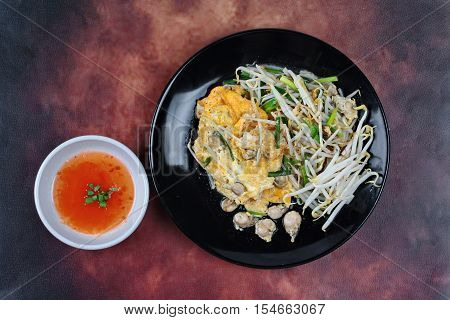Thai food.,Fried egg and oyster with bean sprouts and shallot as Hoi Tod Khai in Thai served with chili sauce.