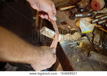 Man working in the shop polished wooden lath