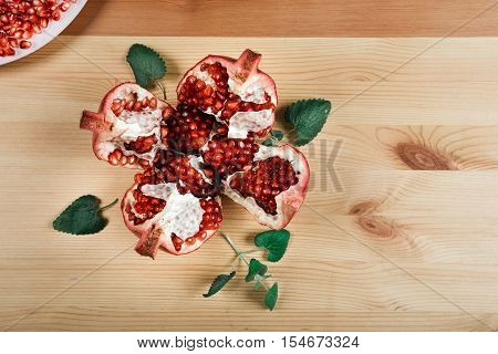 Beautiful ripe pomegranate lying on the wooden light background