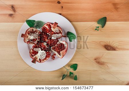 Beautiful ripe pomegranate lying on the wooden light background