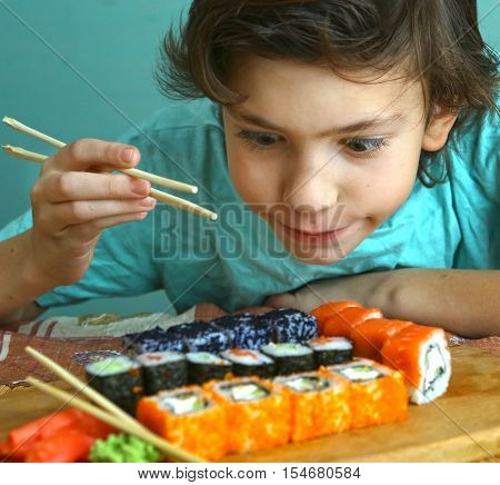 preteen handsome boy with sushi roll set and stick hungry