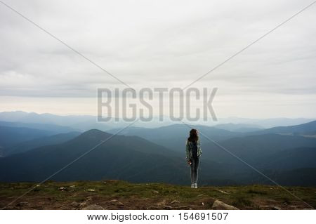 Female person standing on top of Hoverla mountain in front of distant mountains