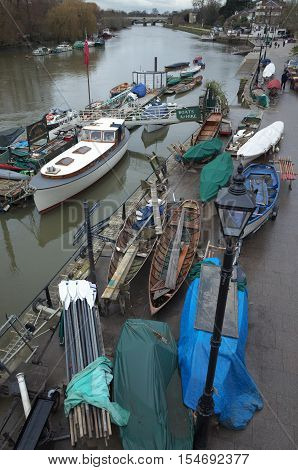 London, England - February 04, 2016: Rowing boats hauled up for maintenance during the winter months at a boatyard along the River Thames at Richmond in London on an overcast and rainy day