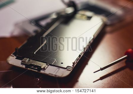 A close-up process of disassemble and dismantle modern mobile phone smartphone with broken shattered display glass and changing details at home