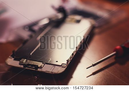 A close-up process of disassemble and dismantle modern mobile phone smartphone with broken shattered display glass and changing details at home