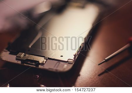 A close-up process of disassemble and dismantle modern mobile phone smartphone with broken shattered display glass and changing details at home