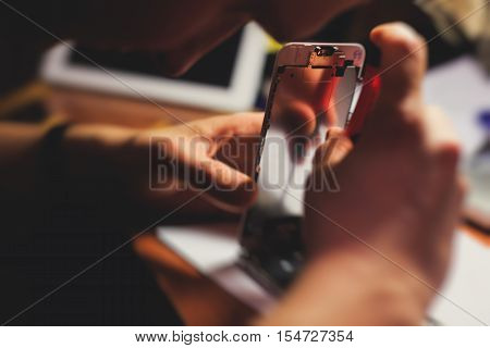 A close-up process of disassemble and dismantle modern mobile phone smartphone with broken shattered display glass and changing details at home